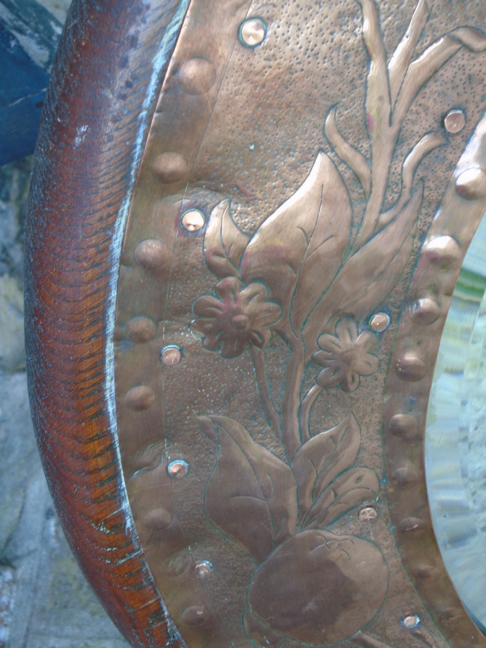 A circular antique Arts and Crafts copper wall mirror featuring hand-hammered repousse decoration of birds, foliage, and urns with a riveted border. View X