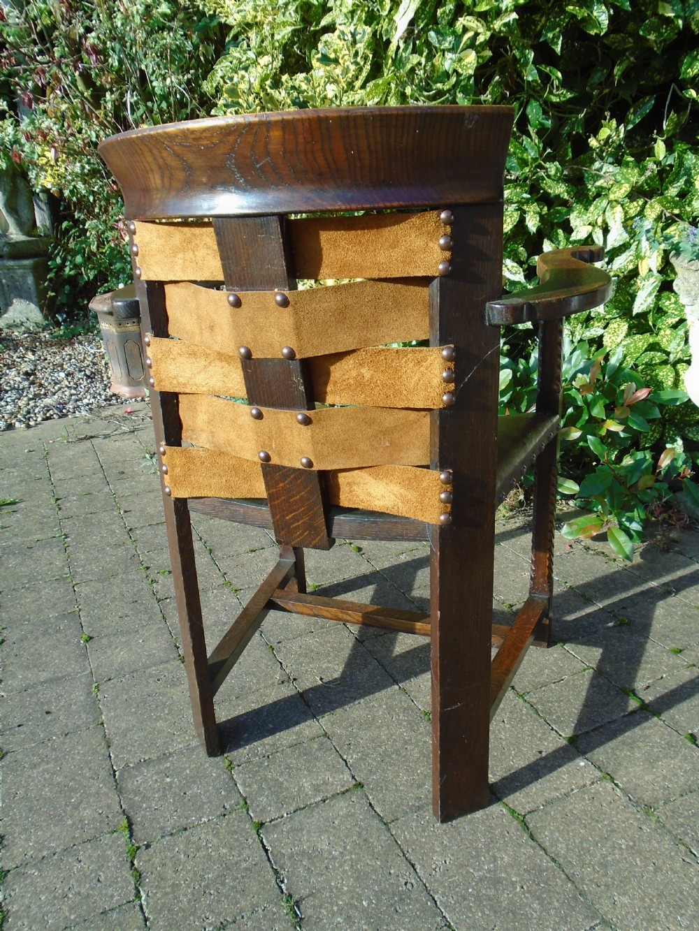 An Arts and Crafts solid oak armchair with carved spiral front legs, a brown leather seat secured with studs, and a curved slatted backrest. View VII