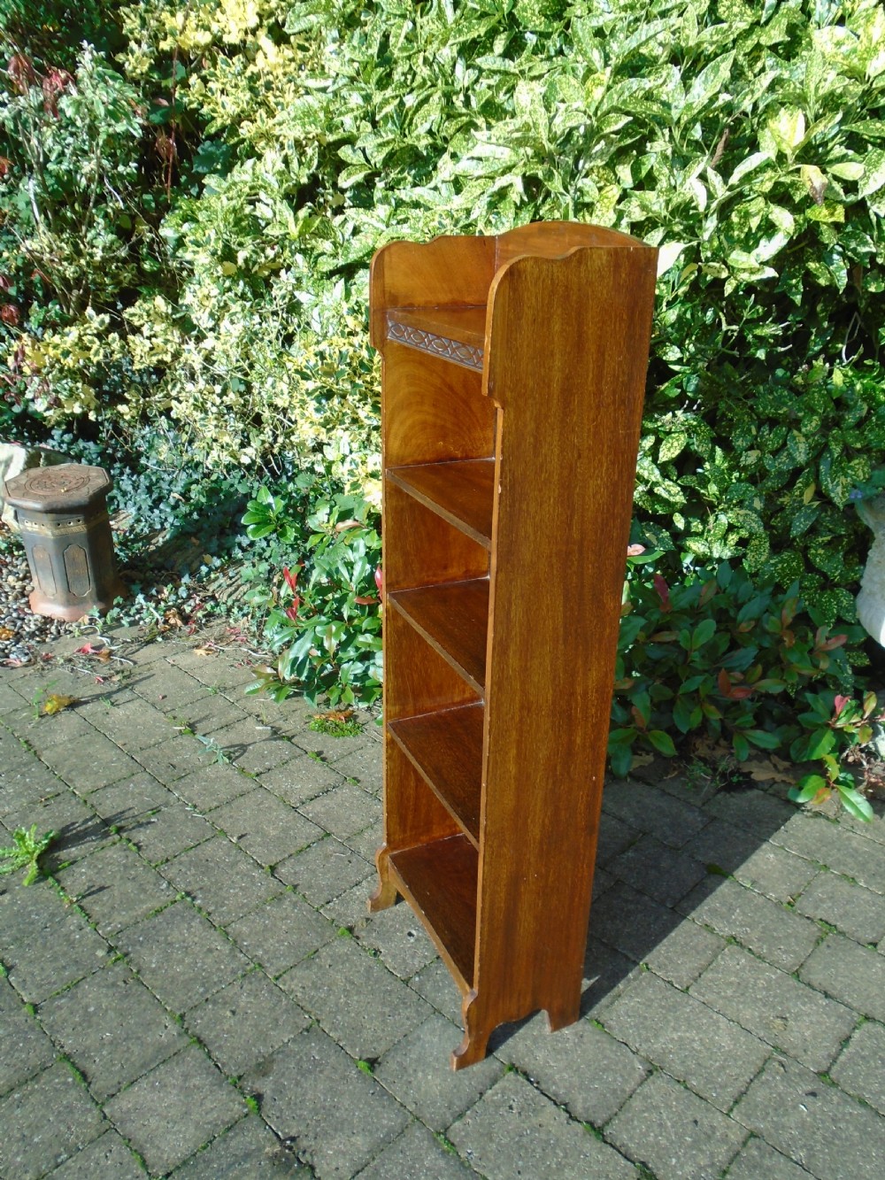A tall, narrow Arts and Crafts walnut open bookcase featuring four shelves and carved decorative details along the upper frieze. View IV