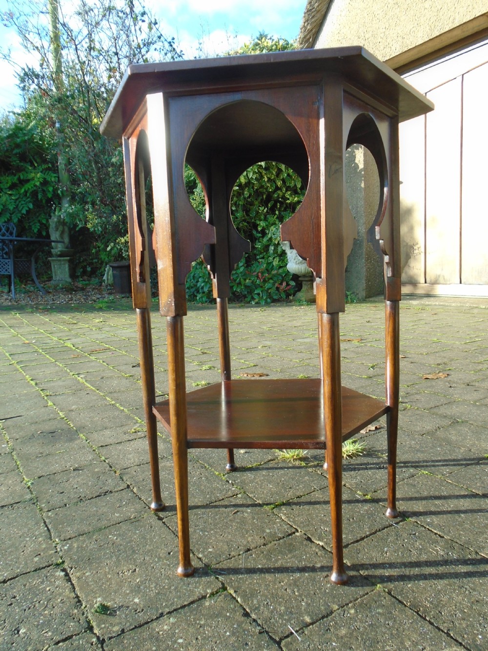 A hexagonal walnut side table featuring carved Moorish horseshoe arches, turned legs, and a lower hexagonal tier. View V