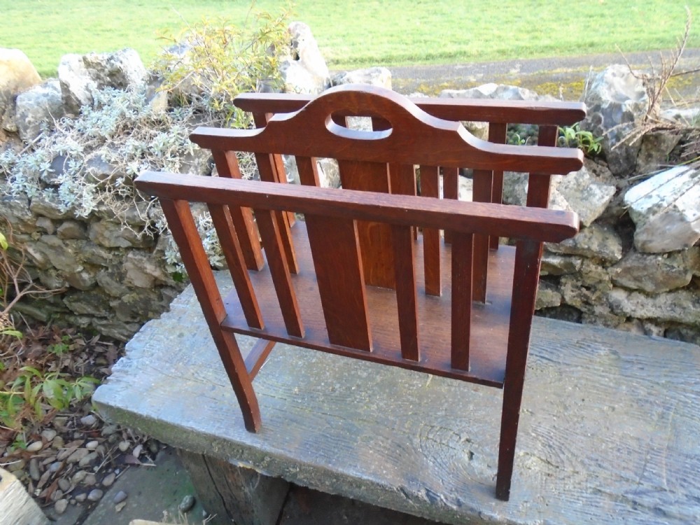 An Arts and Crafts solid oak magazine rack featuring vertical slatted sides, two compartments, and a central shaped divider with a heart cutout handle. View II