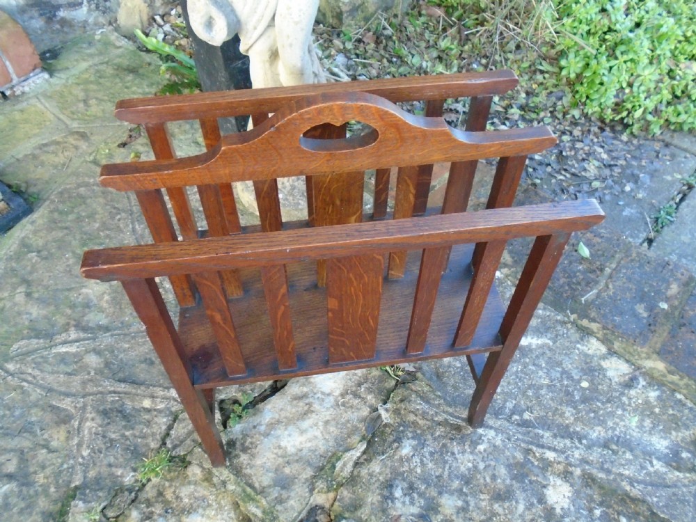 An Arts and Crafts solid oak magazine rack featuring vertical slatted sides, two compartments, and a central shaped divider with a heart cutout handle. View VII