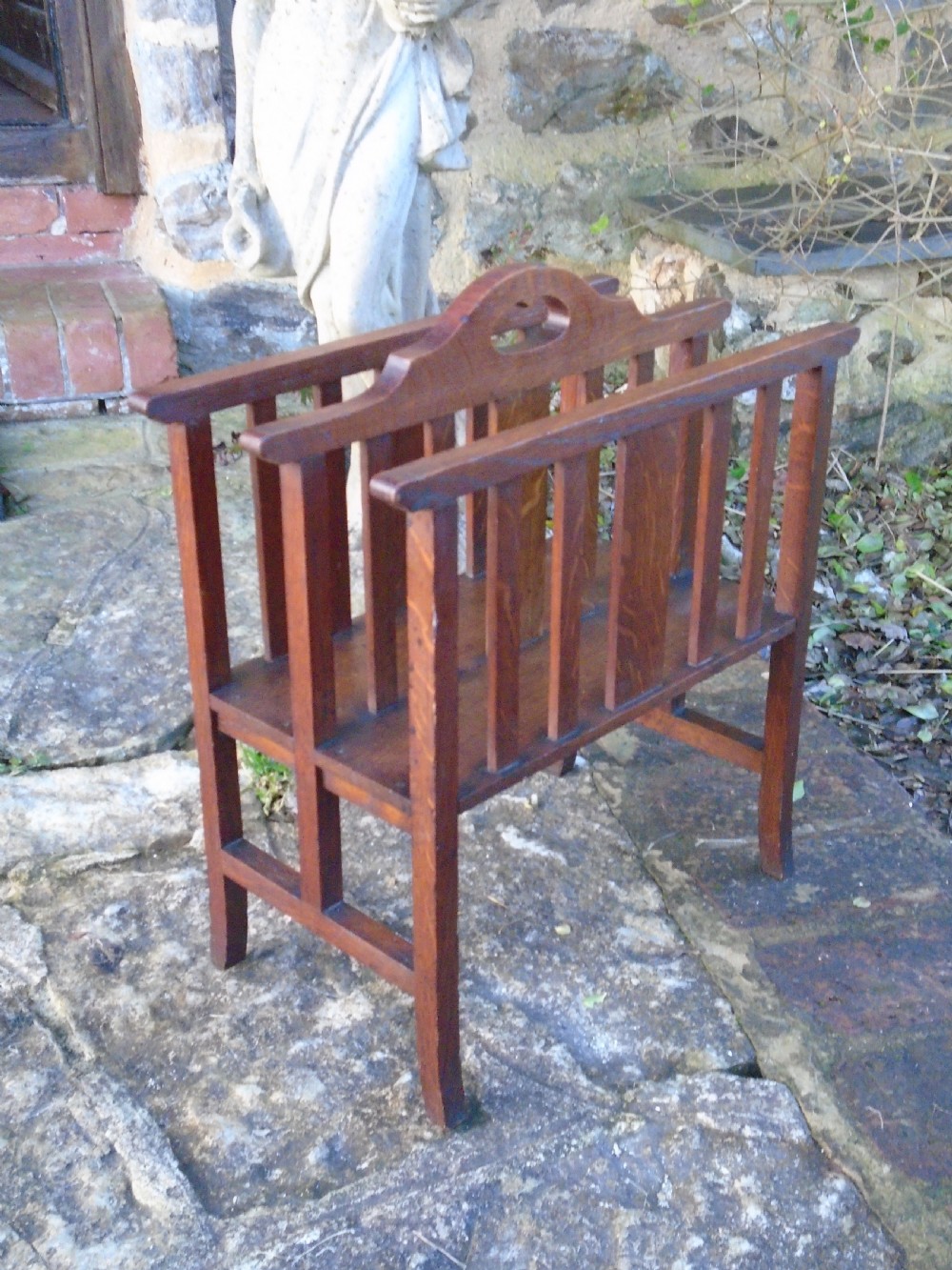 An Arts and Crafts solid oak magazine rack featuring vertical slatted sides, two compartments, and a central shaped divider with a heart cutout handle. View VIII