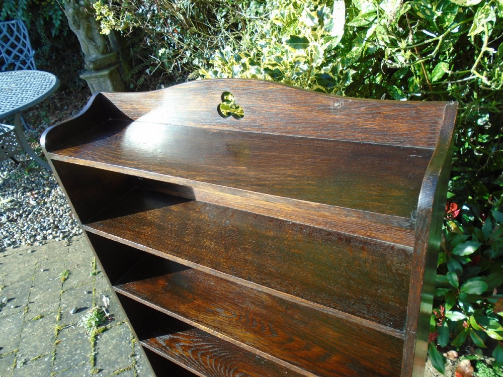 A dark oak Arts and Crafts open bookcase featuring four shelves and a shaped gallery top with a trefoil cutout motif. View III