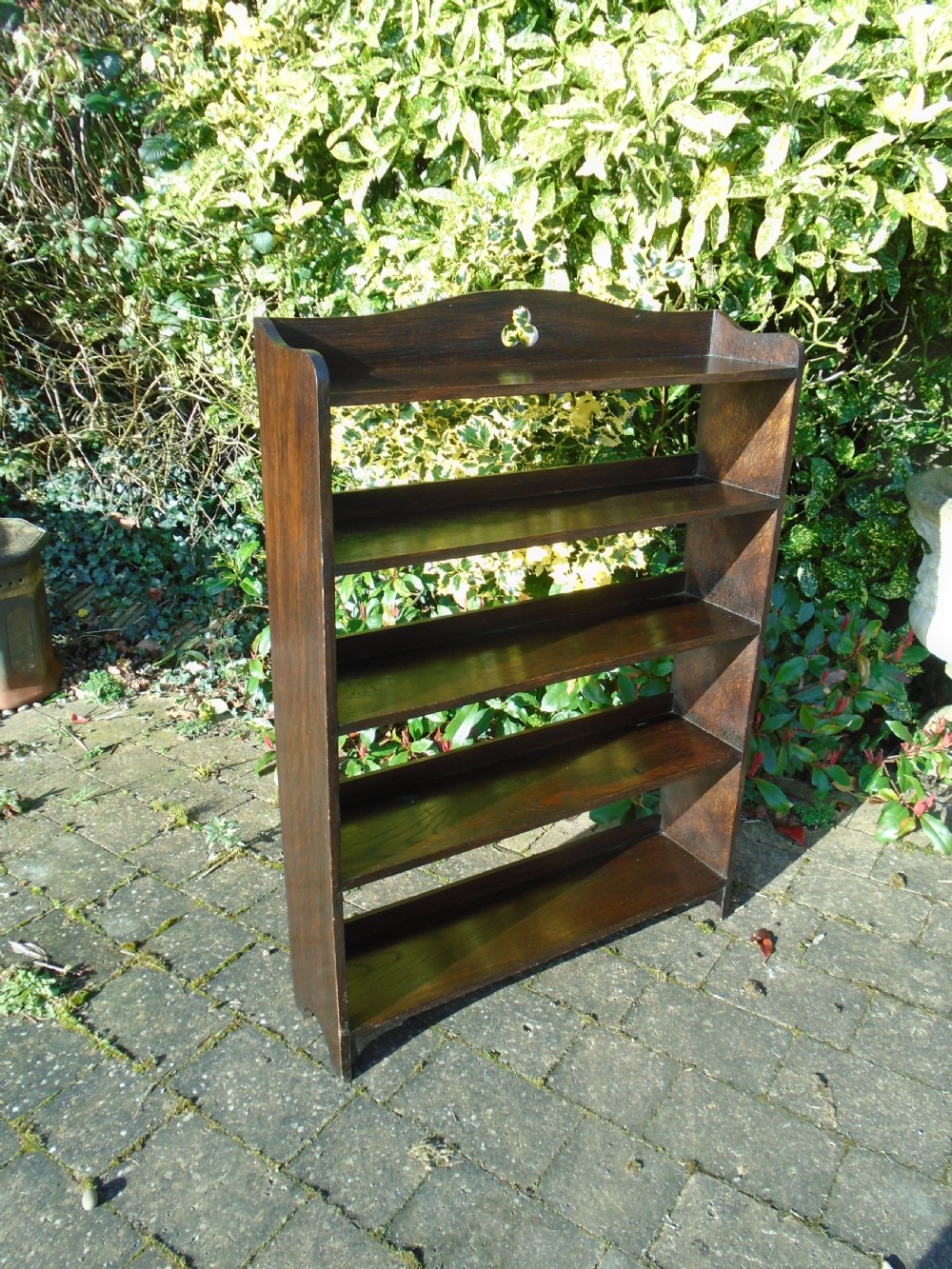 A dark oak Arts and Crafts open bookcase featuring four shelves and a shaped gallery top with a trefoil cutout motif. View IV