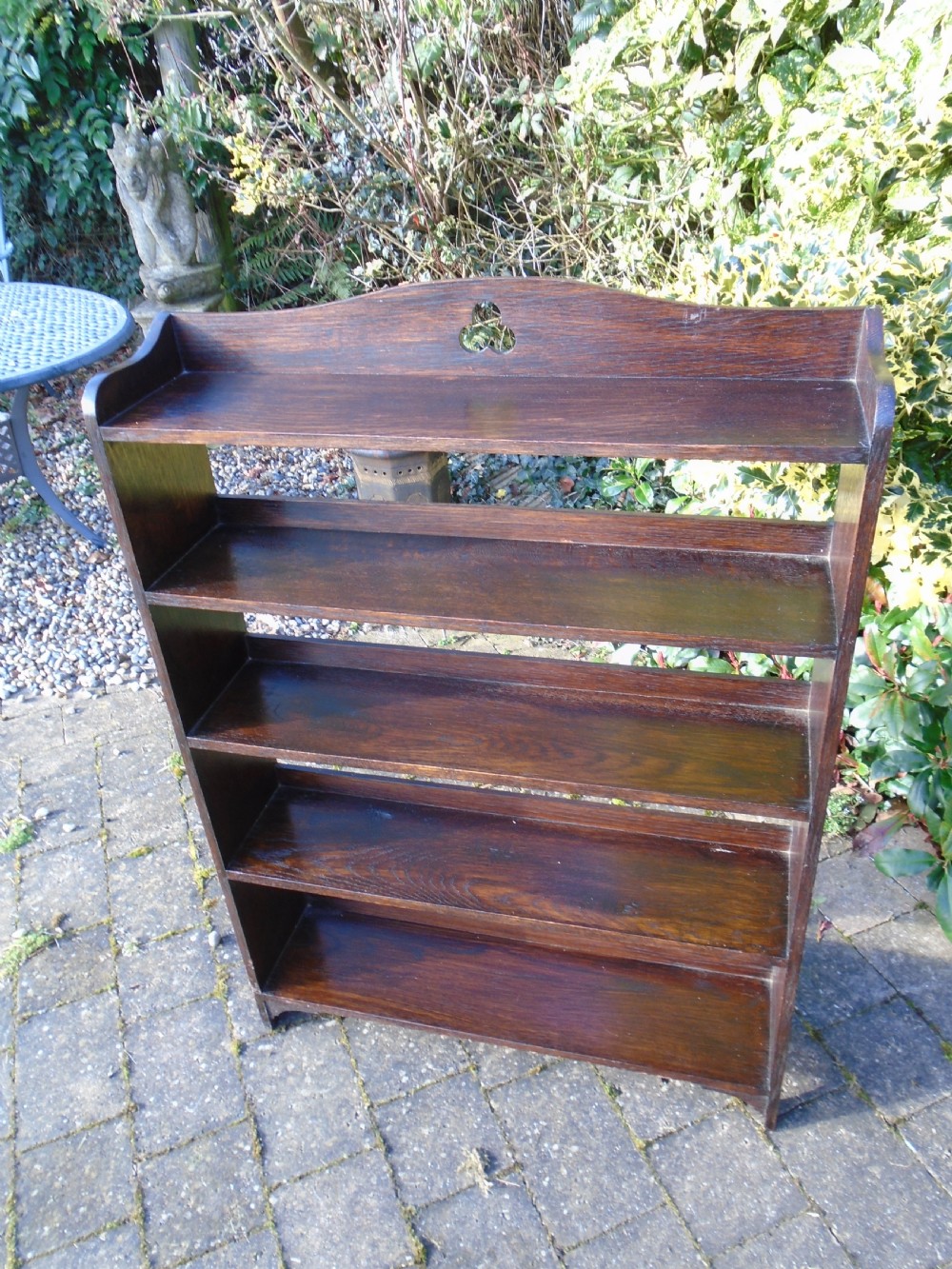 A dark oak Arts and Crafts open bookcase featuring four shelves and a shaped gallery top with a trefoil cutout motif. View V