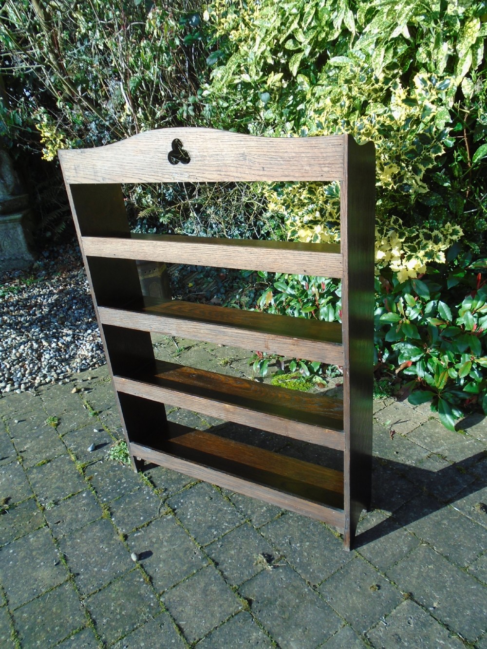 A dark oak Arts and Crafts open bookcase featuring four shelves and a shaped gallery top with a trefoil cutout motif. View VII