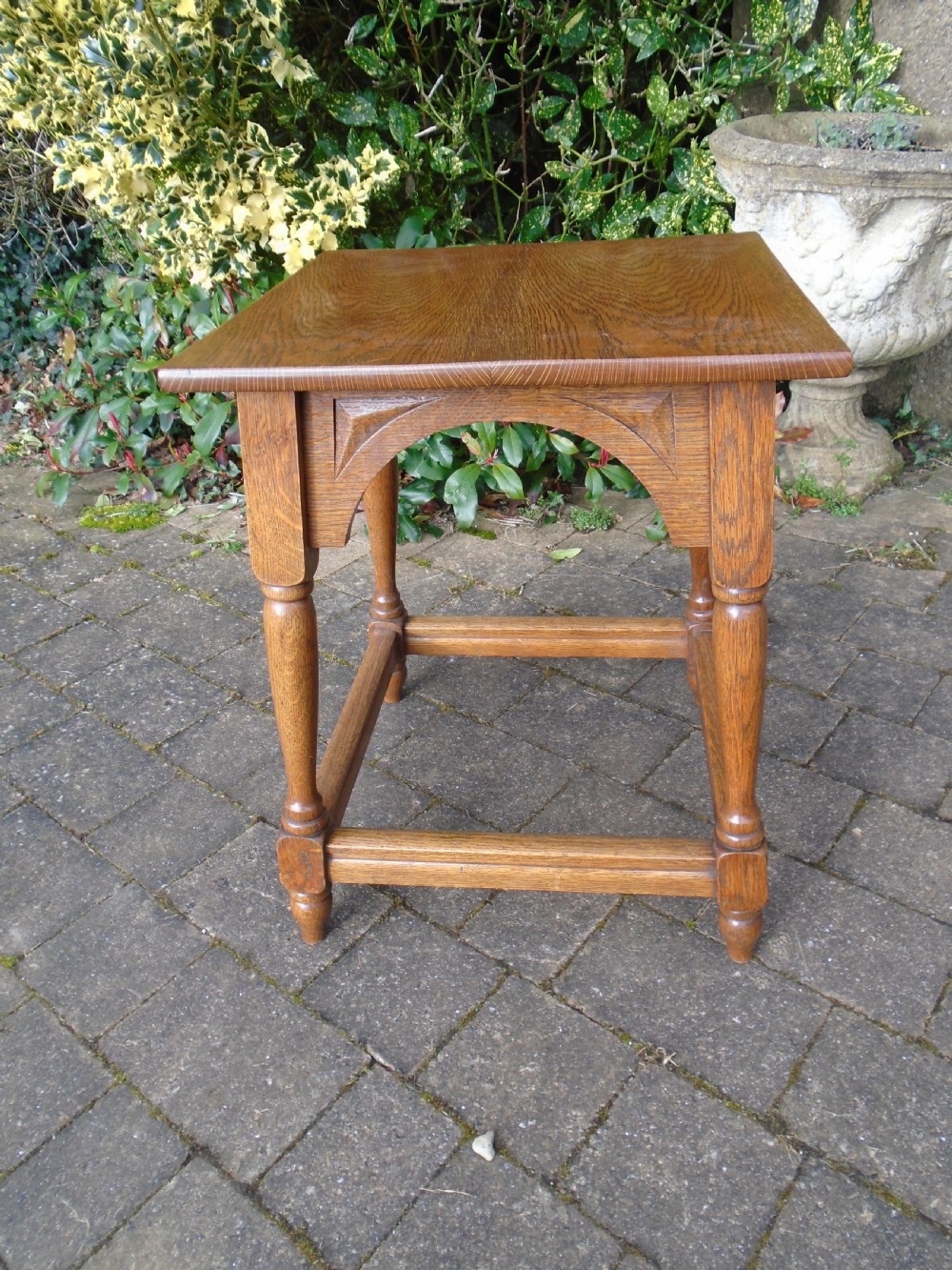 A square oak Arts and Crafts side table featuring arched apron details, turned legs, and a low square stretcher. View II