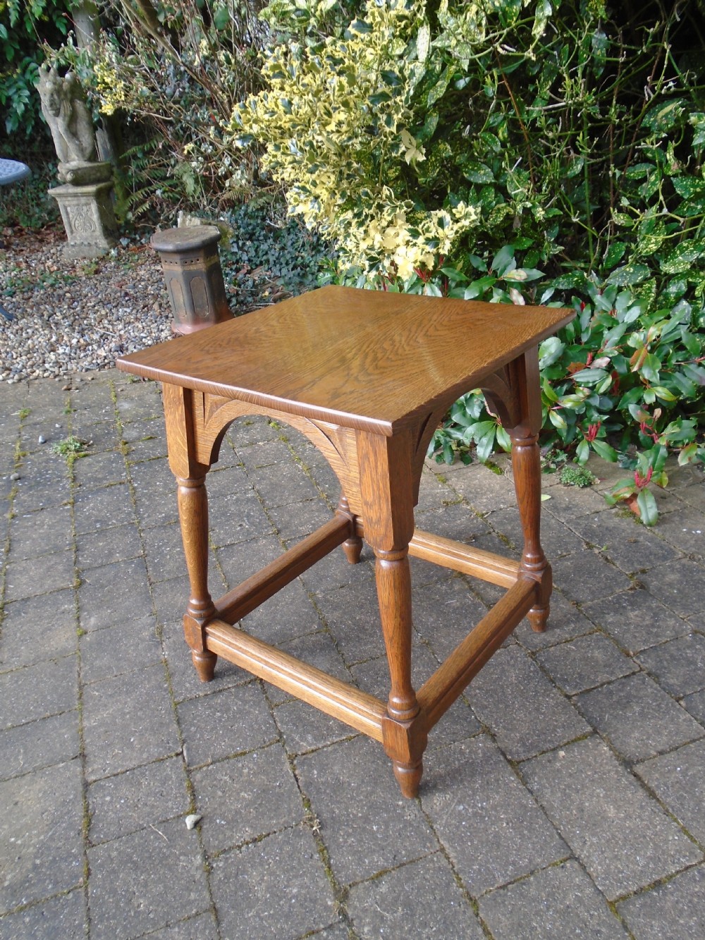 A square oak Arts and Crafts side table featuring arched apron details, turned legs, and a low square stretcher. View III