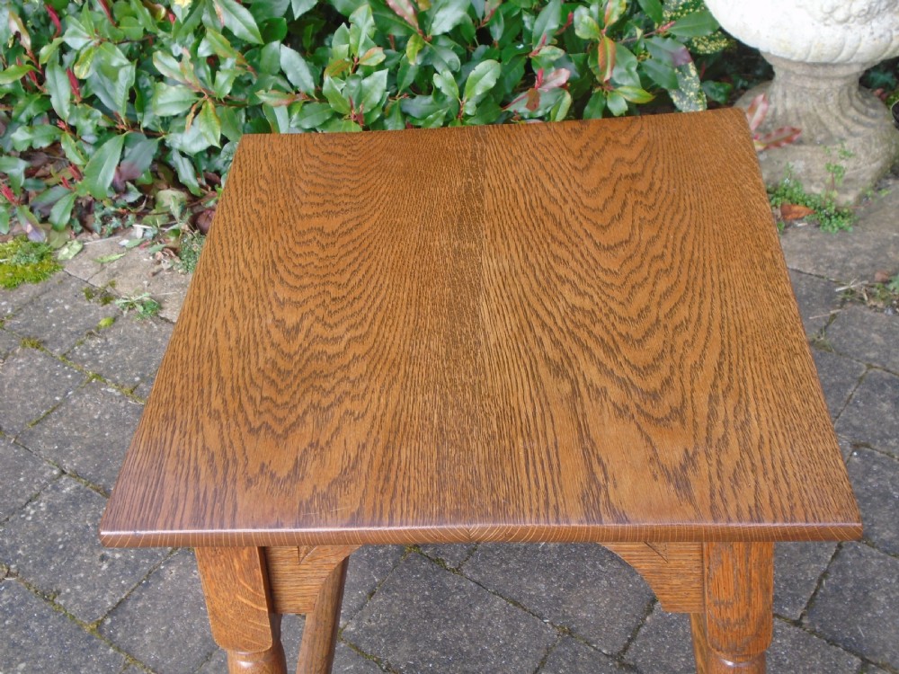 A square oak Arts and Crafts side table featuring arched apron details, turned legs, and a low square stretcher. View V