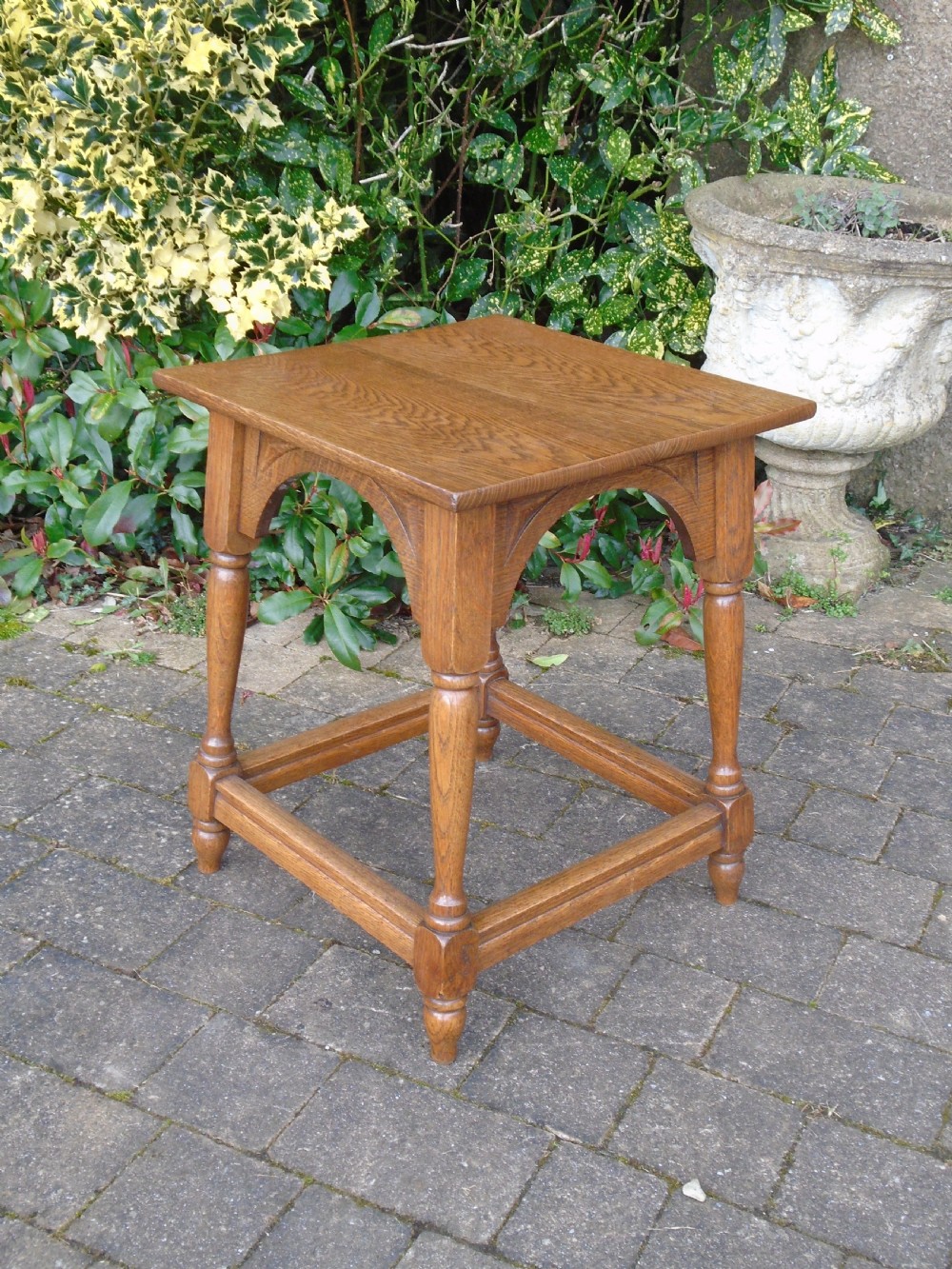 A square oak Arts and Crafts side table featuring arched apron details, turned legs, and a low square stretcher. View VI