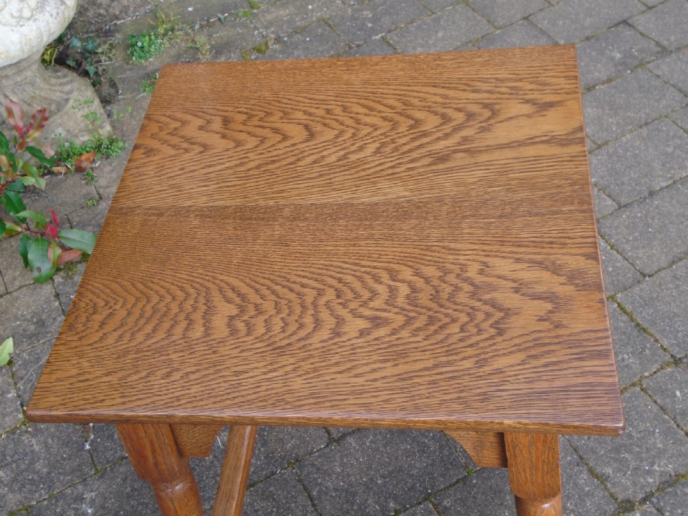 A square oak Arts and Crafts side table featuring arched apron details, turned legs, and a low square stretcher. View VII
