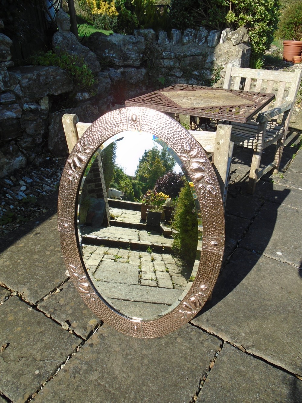 An oval Arts and Crafts mirror featuring a hand-hammered copper frame decorated with embossed pear motifs and decorative raised cabochons. View VII