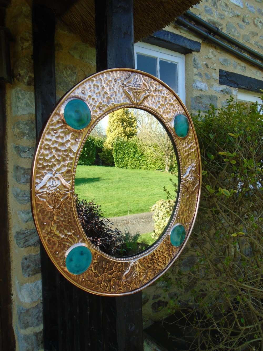An oval Arts and Crafts wall mirror featuring a hand-hammered copper frame decorated with repousse floral motifs and four turquoise round cabochons. View III