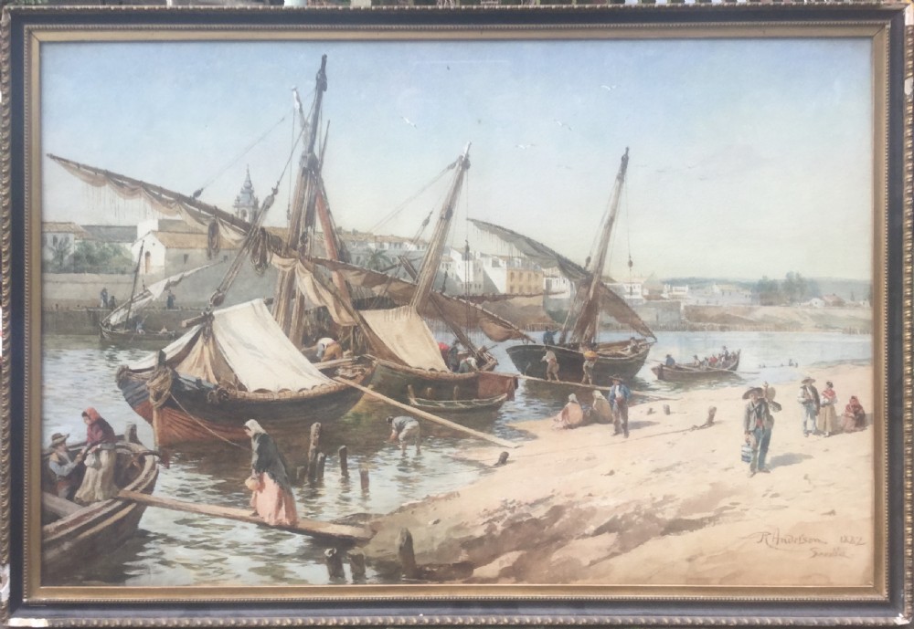 A nineteenth-century watercolour painting depicting wooden sailing boats moored along a sandy riverbank in Seville with figures gathered near the water. View II