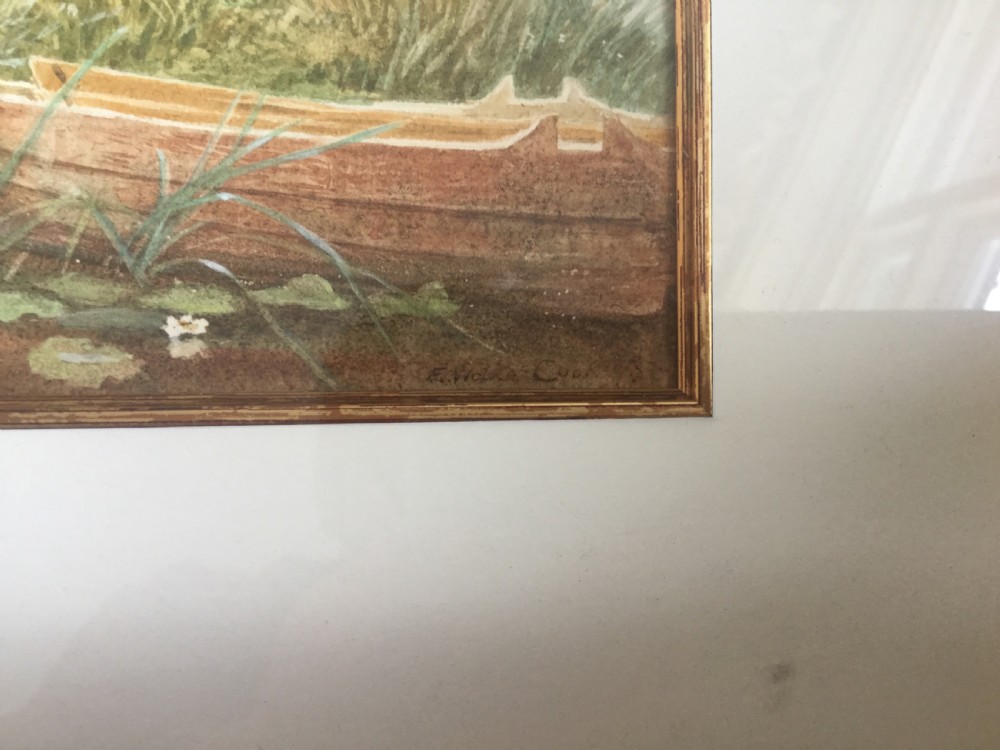 A Victorian watercolour painting depicting a man reclining and a woman seated on a grassy riverbank beside a small wooden boat. View V