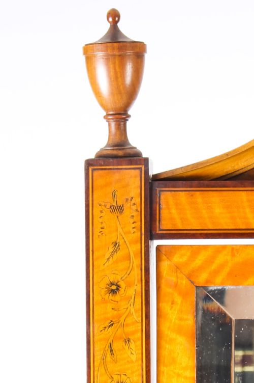 fig 3. An Edwardian satinwood cheval mirror featuring intricate marquetry inlay, an arched pediment with finials, side adjusters, and splayed legs with brass castors.