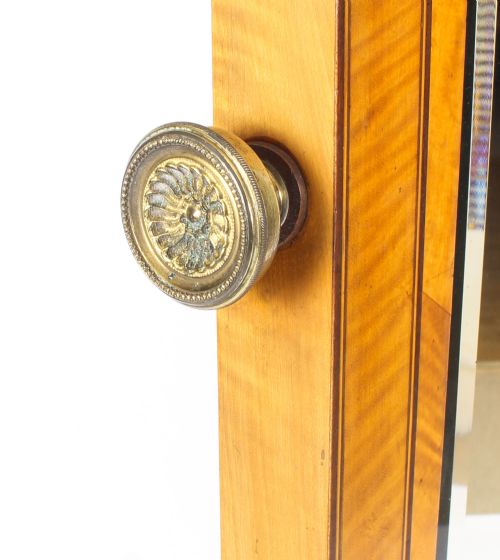 fig 5. An Edwardian satinwood cheval mirror featuring intricate marquetry inlay, an arched pediment with finials, side adjusters, and splayed legs with brass castors.