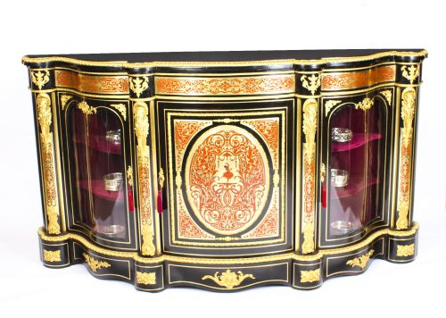 fig 2. A nineteenth-century ebonised serpentine credenza featuring brass and tortoiseshell Boulle marquetry, cast gilt-bronze ormolu mounts, a central panelled door, and glass display sides.