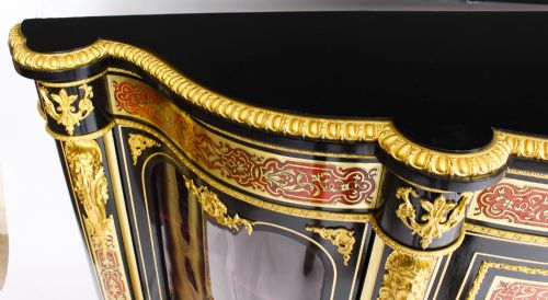 fig 3. A nineteenth-century ebonised serpentine credenza featuring brass and tortoiseshell Boulle marquetry, cast gilt-bronze ormolu mounts, a central panelled door, and glass display sides.