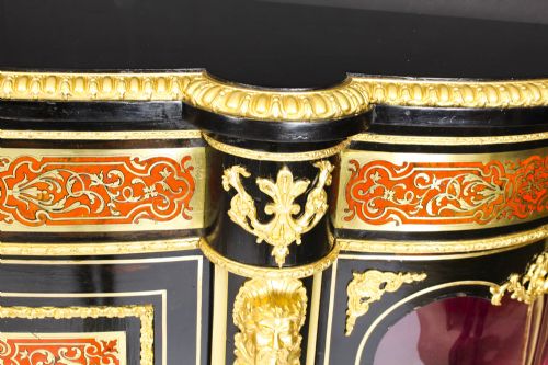 fig 4. A nineteenth-century ebonised serpentine credenza featuring brass and tortoiseshell Boulle marquetry, cast gilt-bronze ormolu mounts, a central panelled door, and glass display sides.