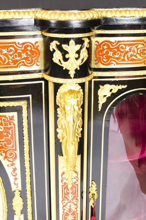 fig 8. A nineteenth-century ebonised serpentine credenza featuring brass and tortoiseshell Boulle marquetry, cast gilt-bronze ormolu mounts, a central panelled door, and glass display sides.