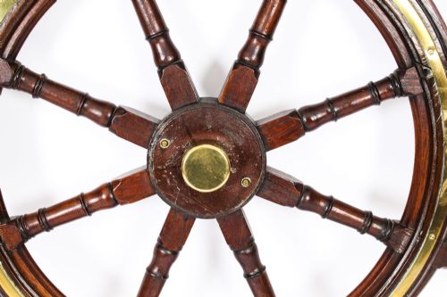 fig 1. A 19th-century eight-spoke teak ships wheel featuring turned wooden handles and a brass inlay ring around the outer helm.