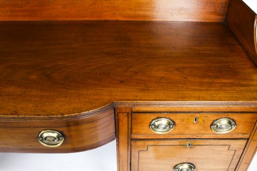 fig 2. A late 18th-century George III mahogany sideboard featuring a raised gallery back, string inlay, central drawer flanked by cupboards, brass ring handles, and turned legs.