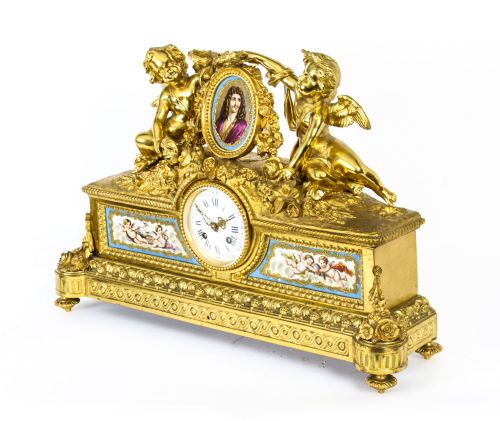 fig 1. An 19th-century French gilt bronze mantel clock with two winged cherubs flanking an oval portrait plaque of Moliere above a porcelain dial.