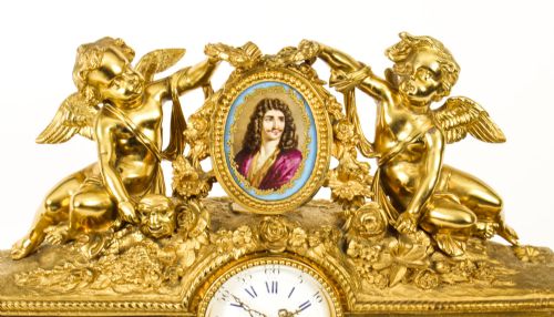 fig 2. An 19th-century French gilt bronze mantel clock with two winged cherubs flanking an oval portrait plaque of Moliere above a porcelain dial.