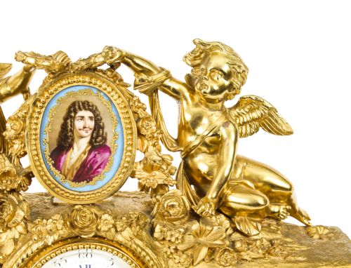 fig 3. An 19th-century French gilt bronze mantel clock with two winged cherubs flanking an oval portrait plaque of Moliere above a porcelain dial.