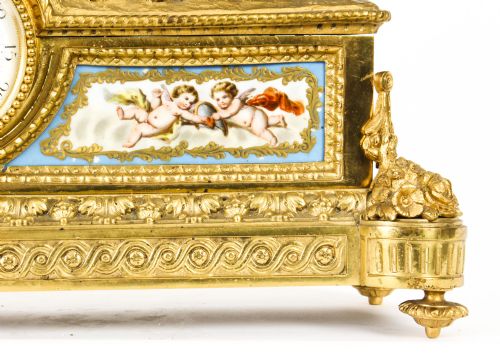 fig 9. An 19th-century French gilt bronze mantel clock with two winged cherubs flanking an oval portrait plaque of Moliere above a porcelain dial.