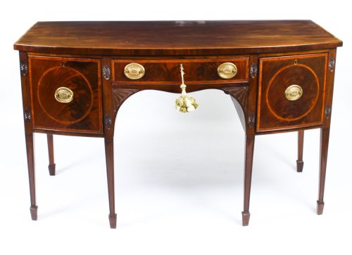 fig 1. An 18th-century George III flame mahogany sideboard featuring circular inlaid panels, brass ring handles, and square tapered legs.