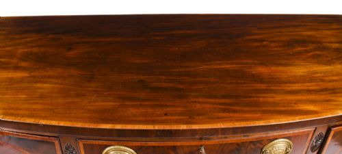 fig 3. An 18th-century George III flame mahogany sideboard featuring circular inlaid panels, brass ring handles, and square tapered legs.