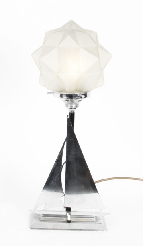 fig 3. An Art Deco chrome table lamp featuring a stylized sailboat stem set upon a stepped rectangular base, topped with a faceted frosted glass shade.