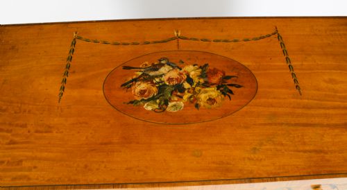 fig 5. A pair of 19th-century Adam Revival painted satinwood side cabinets featuring painted oval musical medallions, draped garlands, single top drawers, double cupboards, and turned tapered legs.