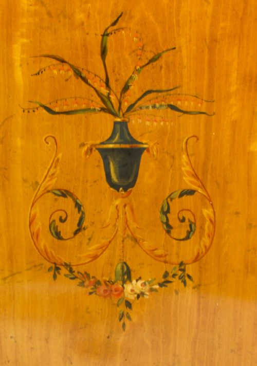fig 8. A pair of 19th-century Adam Revival painted satinwood side cabinets featuring painted oval musical medallions, draped garlands, single top drawers, double cupboards, and turned tapered legs.