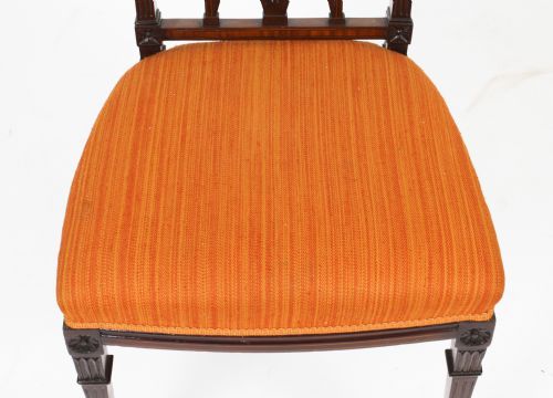 fig 5. A pair of antique Sheraton Revival mahogany side chairs featuring carved arched back tracery, turned front legs, and orange striped fabric seats.