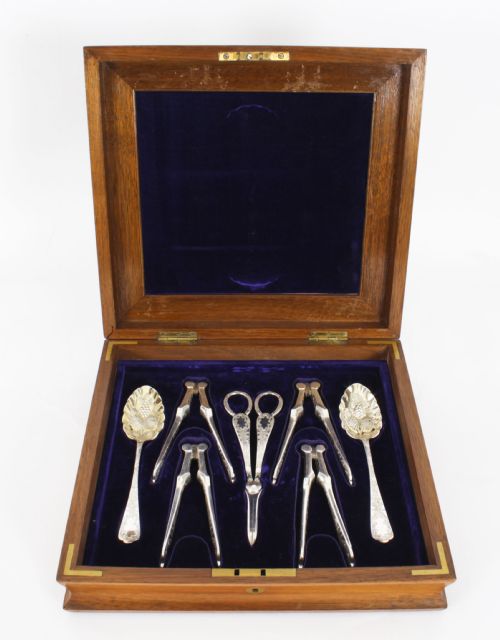 fig 2. An open wooden case lined with deep purple velvet containing a silver-plated fruit serving set with embossed spoons and nutcrackers.