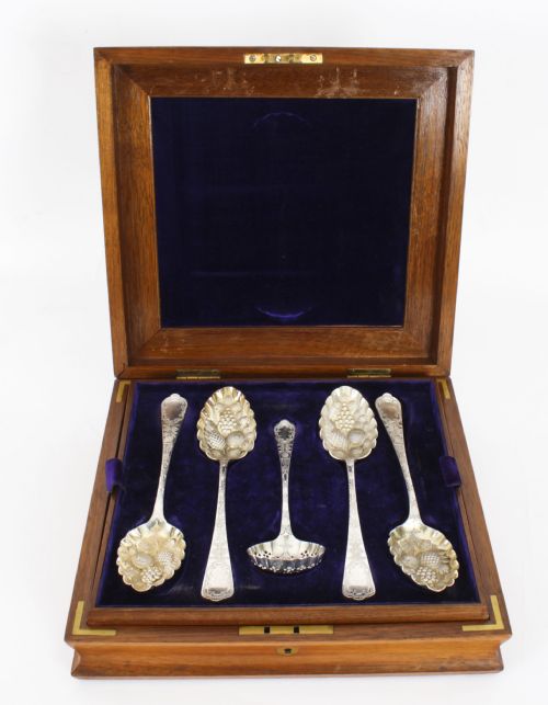 fig 3. An open wooden case lined with deep purple velvet containing a silver-plated fruit serving set with embossed spoons and nutcrackers.