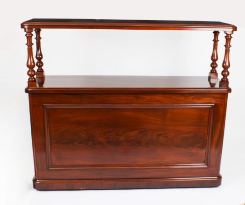 fig 1. A Victorian flame mahogany dry bar featuring an elevated upper shelf supported by four turned balusters over a panelled lower counter.
