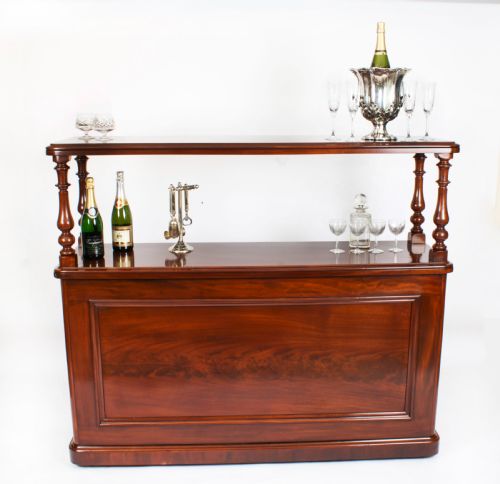 fig 2. A Victorian flame mahogany dry bar featuring an elevated upper shelf supported by four turned balusters over a panelled lower counter.