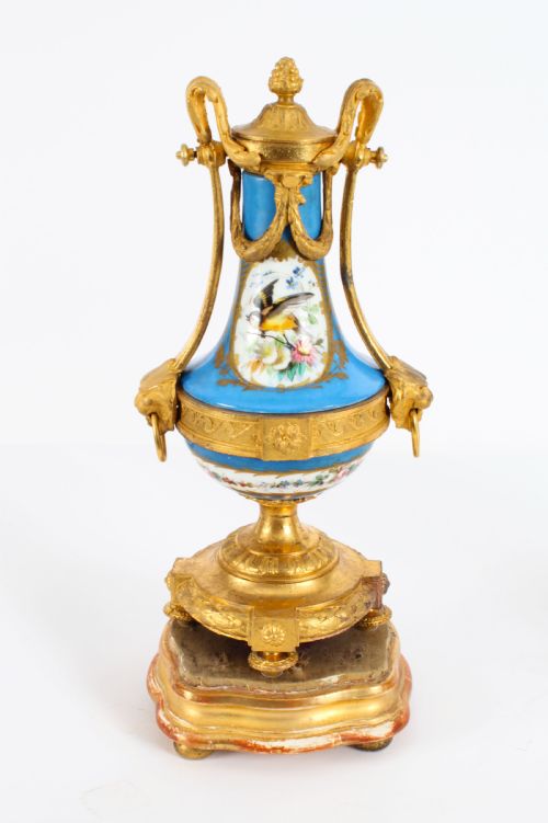 fig 1. A pair of 19th-century French Sevres-style bleu celeste porcelain urns featuring hand-painted floral and bird reserves, supported by gilt metal mounts and pedestals.