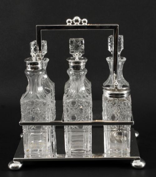 fig 1. A Victorian silver-plated rectangular cruet stand holding six faceted cut-glass condiment bottles with metal tops and glass stoppers.
