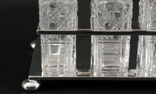 fig 3. A Victorian silver-plated rectangular cruet stand holding six faceted cut-glass condiment bottles with metal tops and glass stoppers.