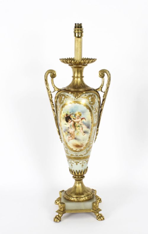 fig 1. A 19th-century French Sevres-style porcelain urn lamp painted with cherubs, featuring gilt bronze handles, foliage mounts, and an onyx base.