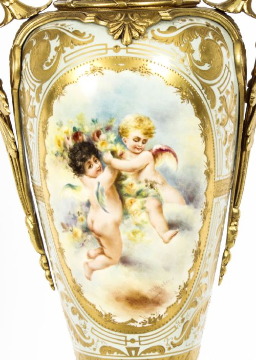 fig 2. A 19th-century French Sevres-style porcelain urn lamp painted with cherubs, featuring gilt bronze handles, foliage mounts, and an onyx base.