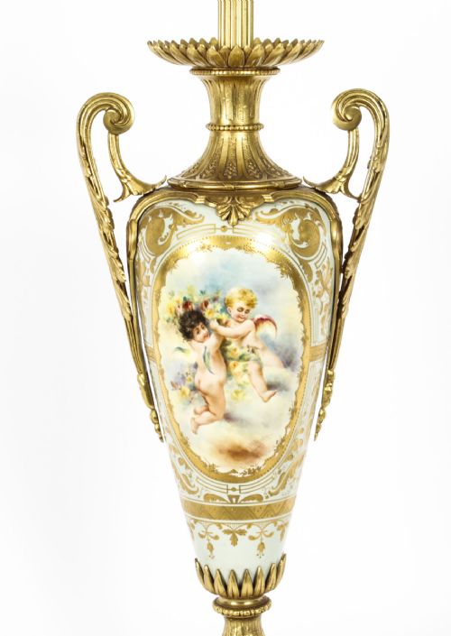 fig 3. A 19th-century French Sevres-style porcelain urn lamp painted with cherubs, featuring gilt bronze handles, foliage mounts, and an onyx base.