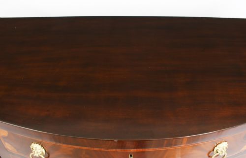 fig 3. An 18th-century George III flame mahogany serpentine sideboard featuring inlaid circular panel doors, brass lion-mask ring handles, and tapered square legs terminating in spade feet.