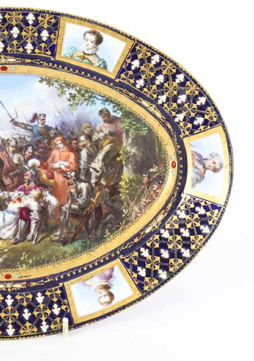 fig 4. An antique French oval porcelain dish featuring a central hand-painted historical battle scene surrounded by a cobalt blue border with gilt lattice work and portrait cartouches.